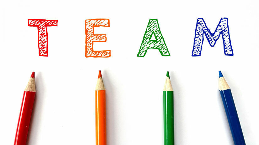 チームワークと品質をアピールする写真。  写真には、「TEAM」の文字の下に色鉛筆が4本並べられている。色鉛筆は、それぞれ異なる色で、チームワークと品質を象徴している。  この写真は、チームワークと品質をアピールしている。